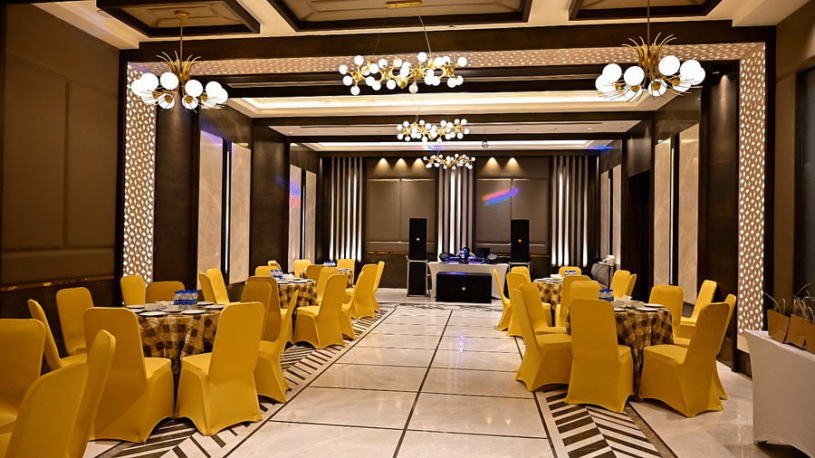 Event space with round tables and chairs arranged, featuring fancy lights hanging from the ceiling at BluSalzz Residence, Amritsar